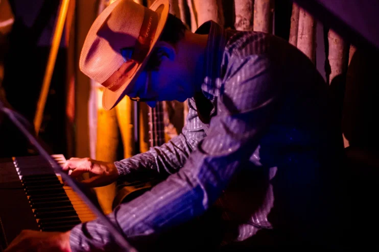 Happy Montana playing piano in warm stage light during a live session